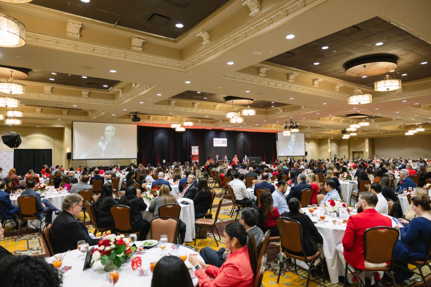 Wide ballroom shot during the Cougar 100 luncheon, stage and hundreds of attendees visible