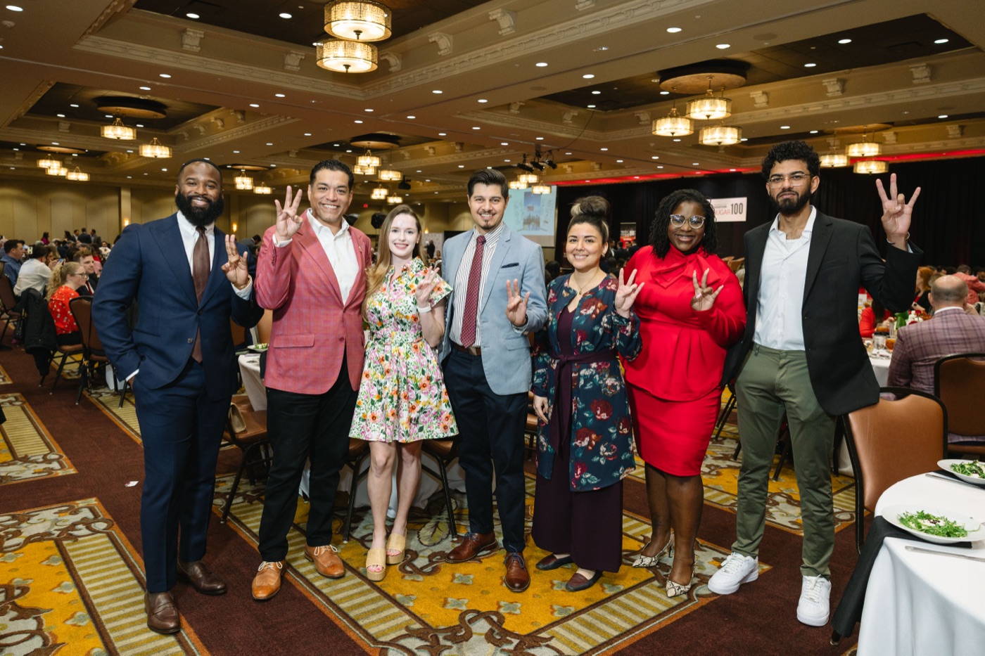 The Brillion Studio group flashing the UH Cougars hand sign at their table
