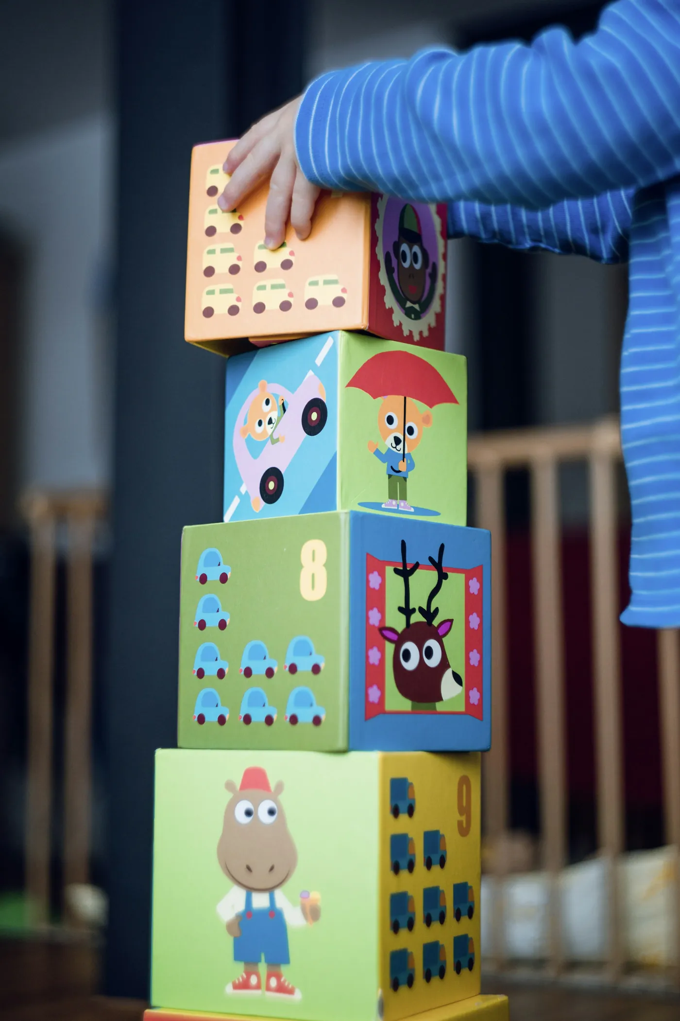 A tower of stacked picture blocks beside a small child&rsquo;s hand