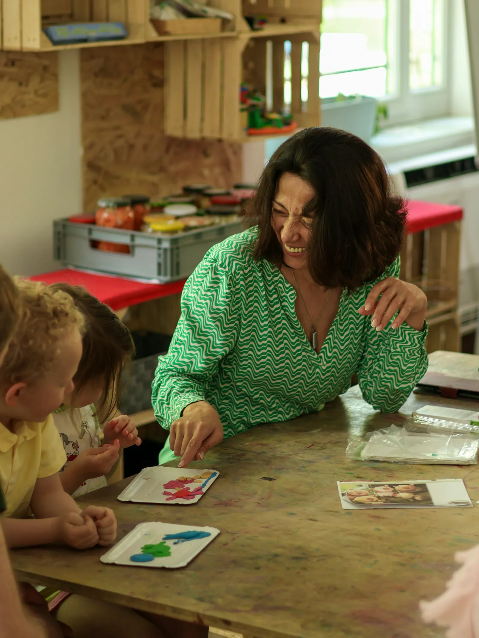 A teacher playing a card game with young children at a classroom table