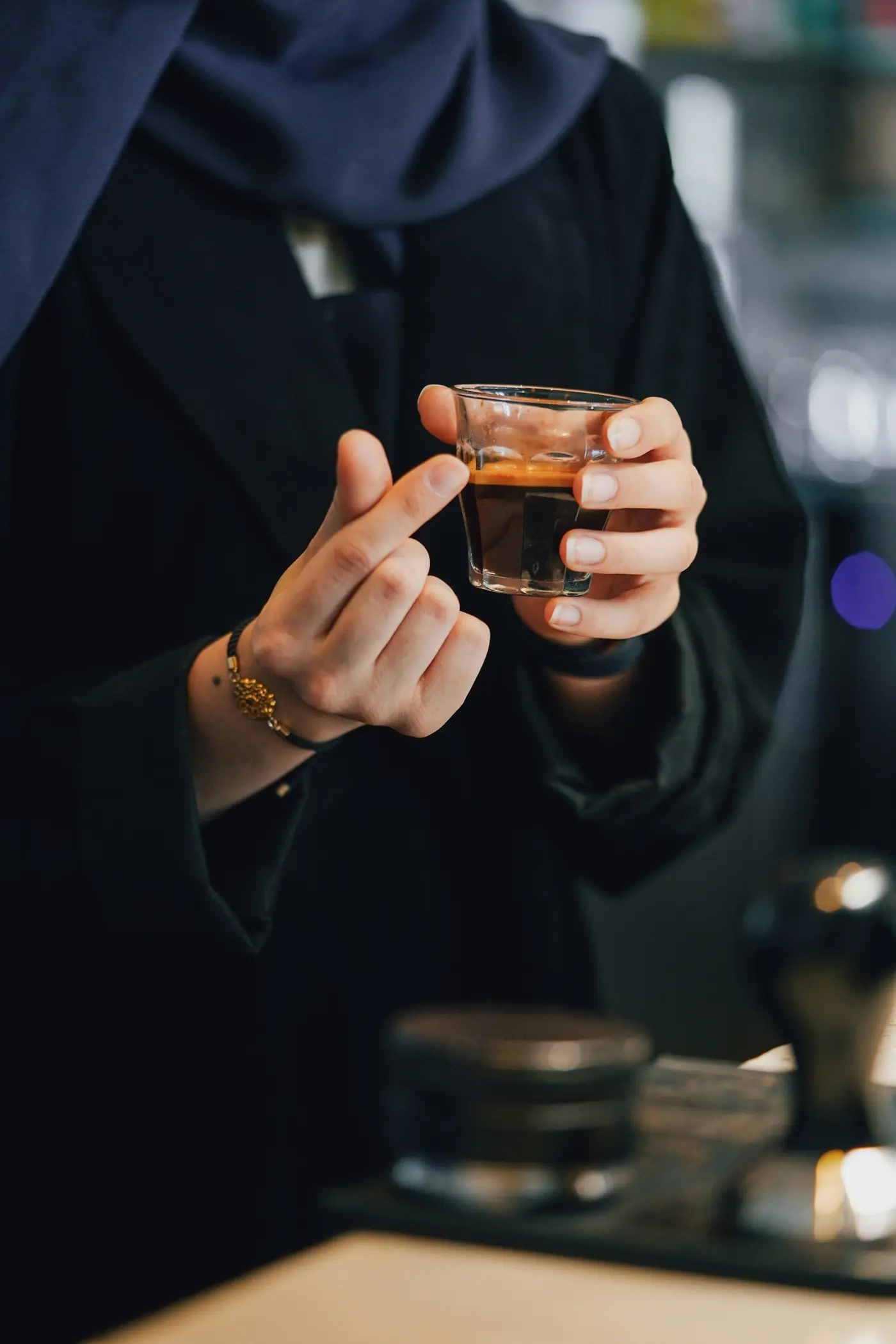 Two hands holding a small glass of tea