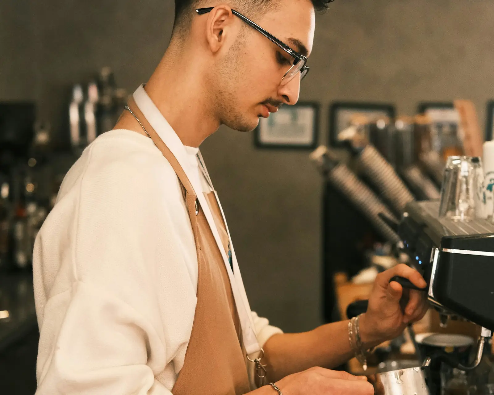 A barista steaming milk at an espresso machine