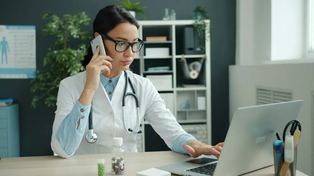 A clinician on the phone at a laptop