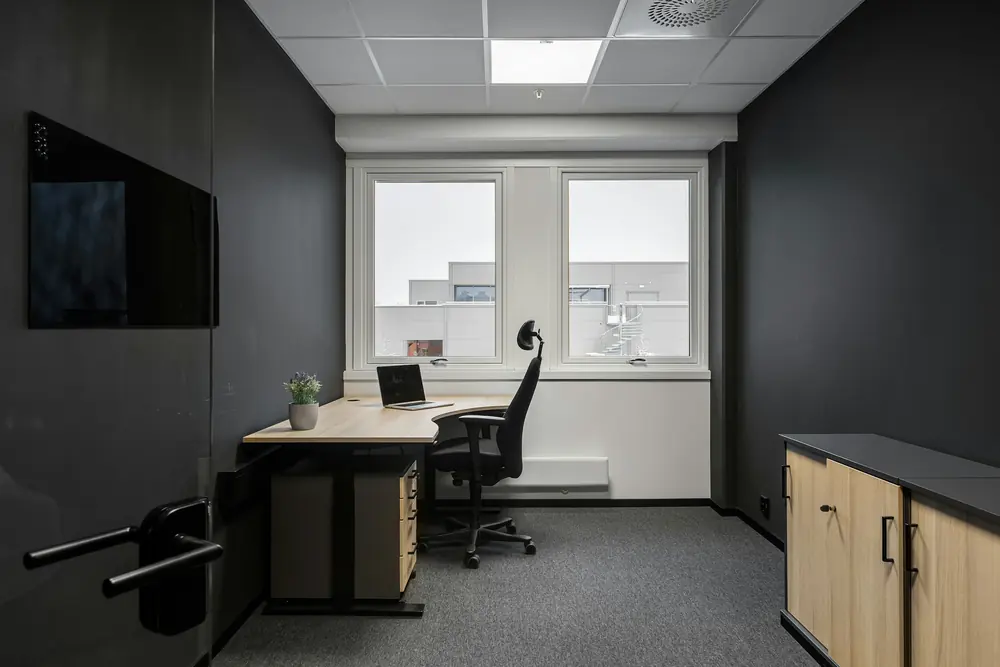 An empty office with a desk and chair in front of the window