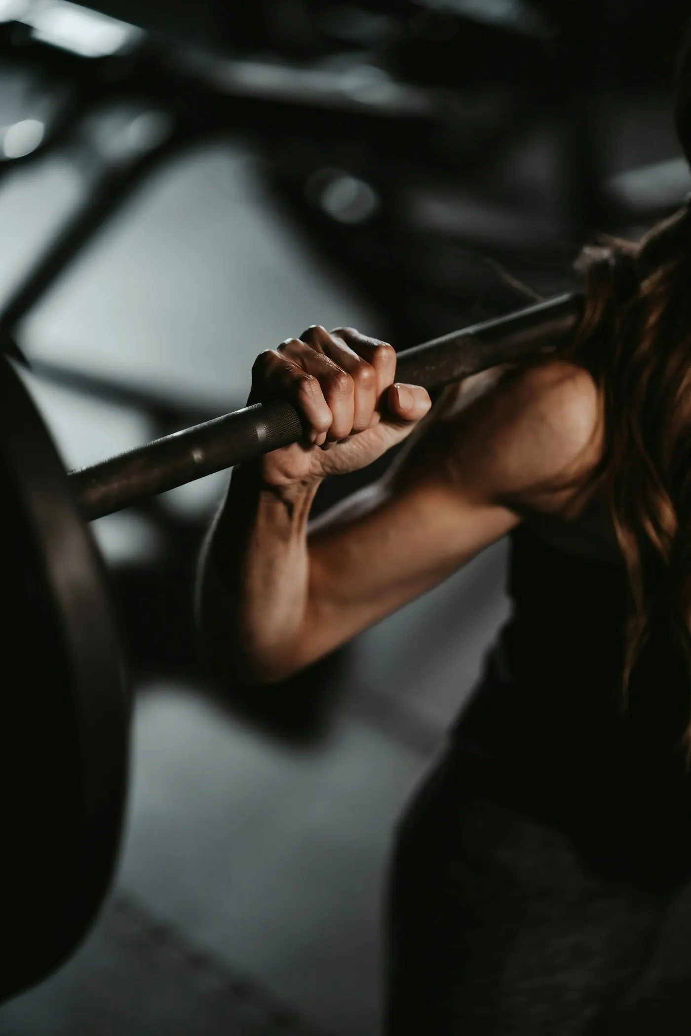 Two hands gripping a loaded barbell across a lifter's shoulders