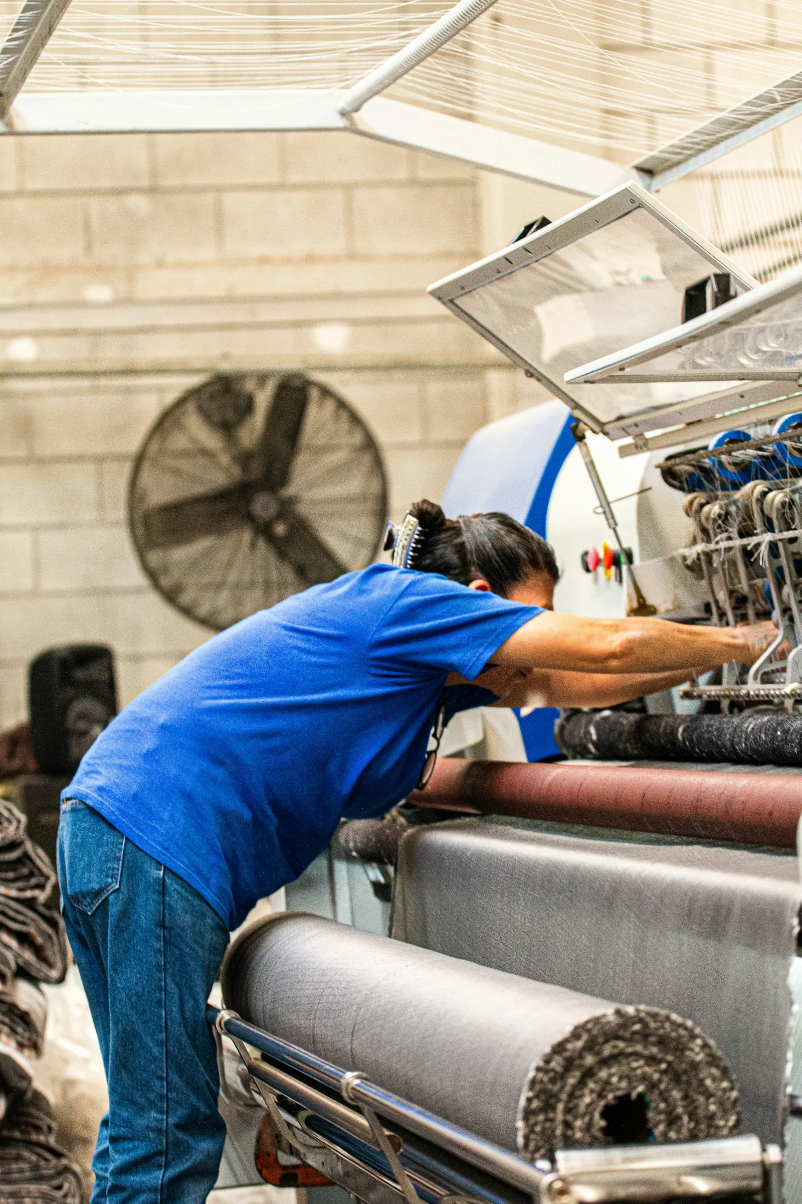 A worker feeding a rug through a washing machine