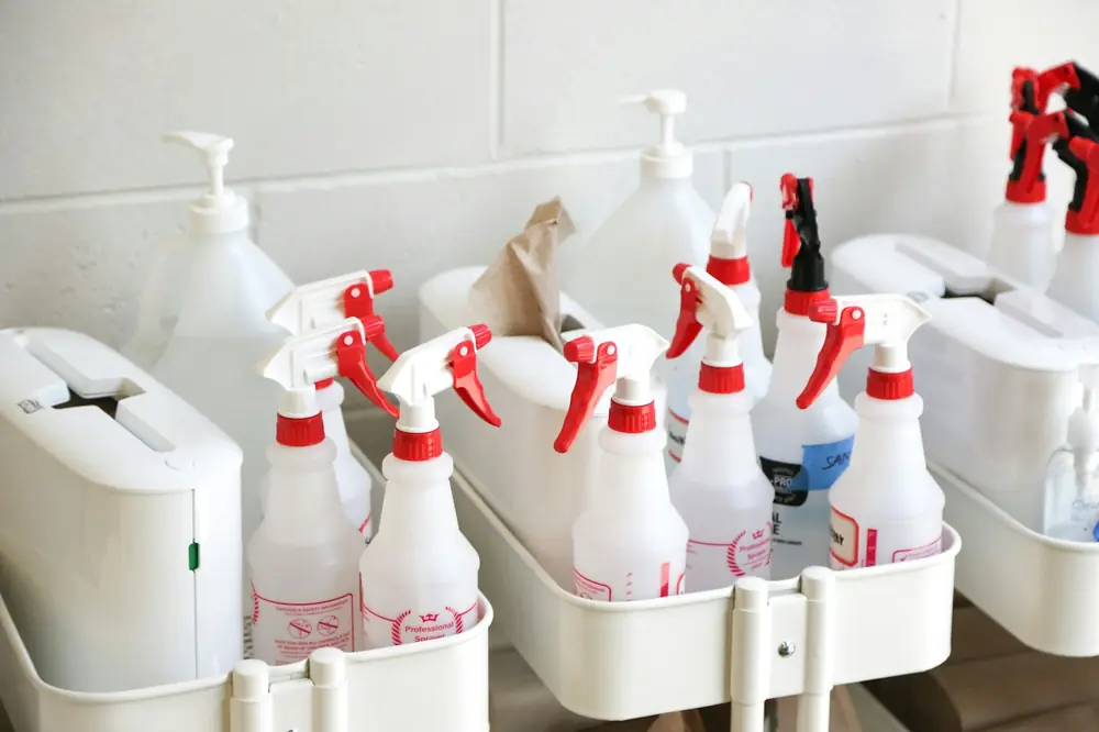 A row of white spray bottles in a cleaning caddy