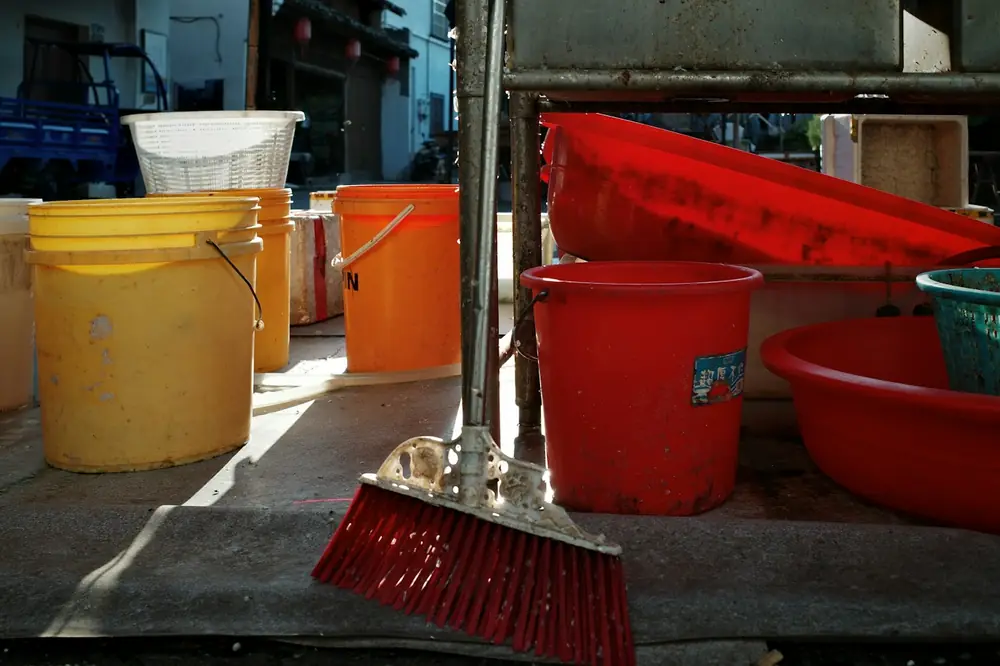Buckets and a broom left against a wall