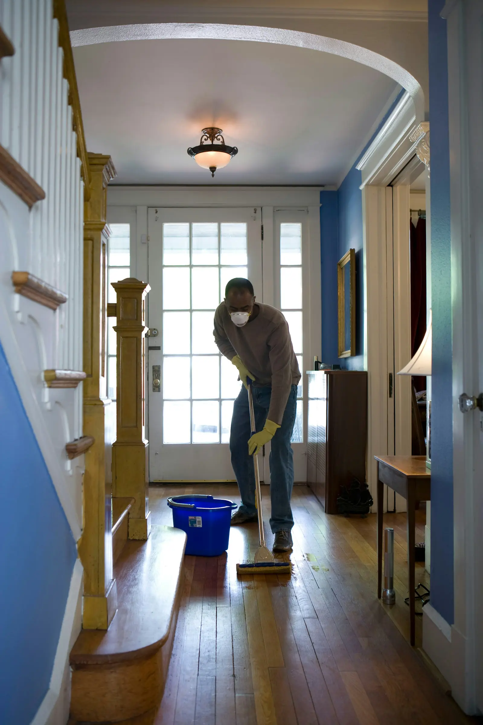 A cleaner mopping a wood-floored hallway