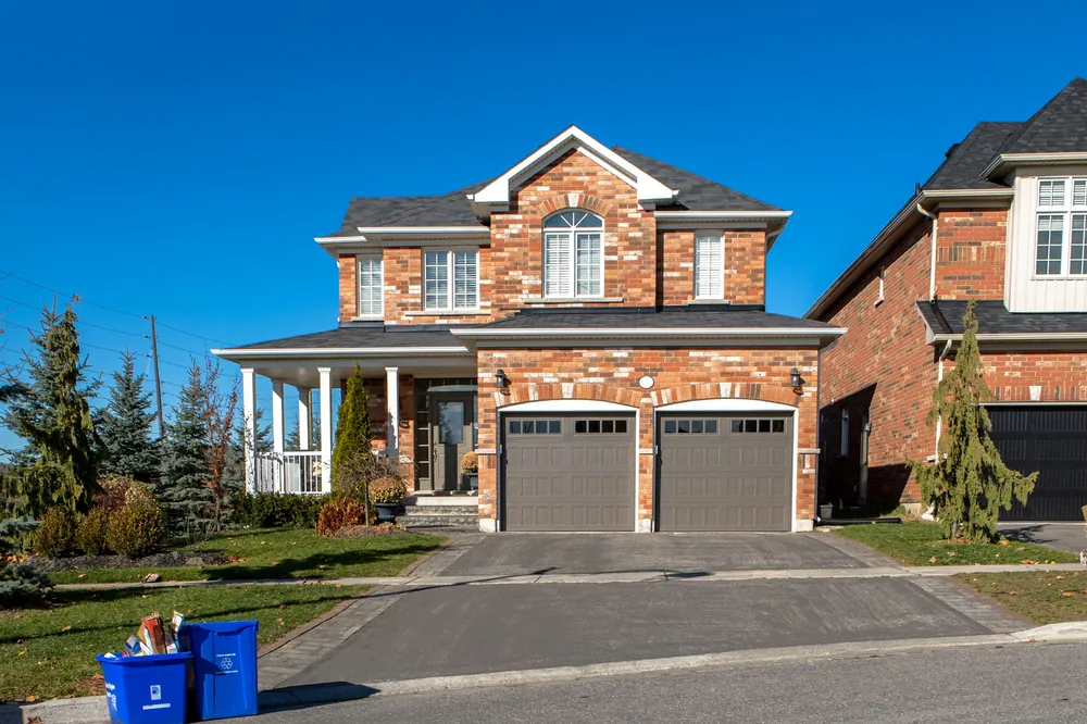 A brick house with two garage doors and a wide driveway