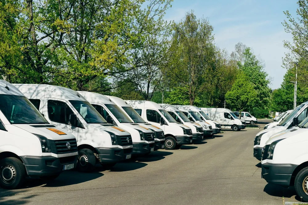 A long row of identical white service vans in a parking lot