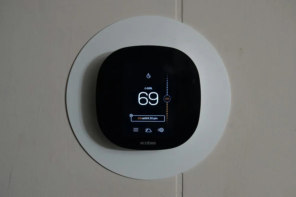 A smart thermostat on a wall reading 69 degrees