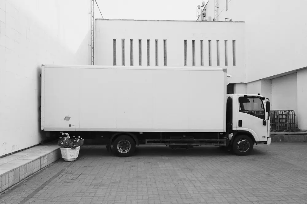 A white box truck parked on its own beside a building