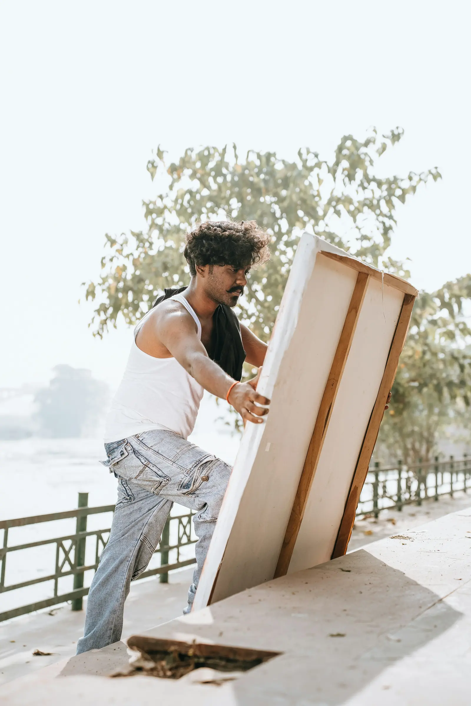 A mover carrying a tall flat piece of furniture along a path