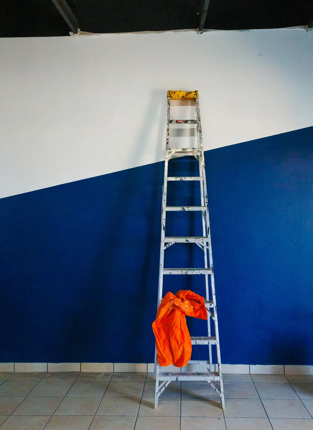 A ladder standing against a half-painted blue wall