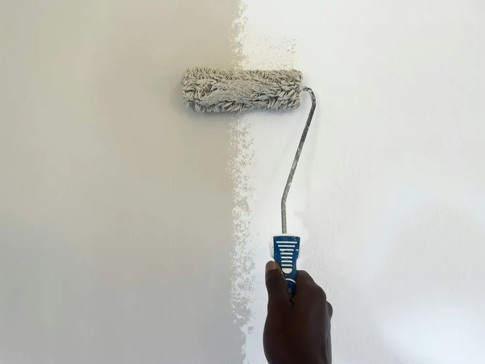 A paint roller halfway up a white wall