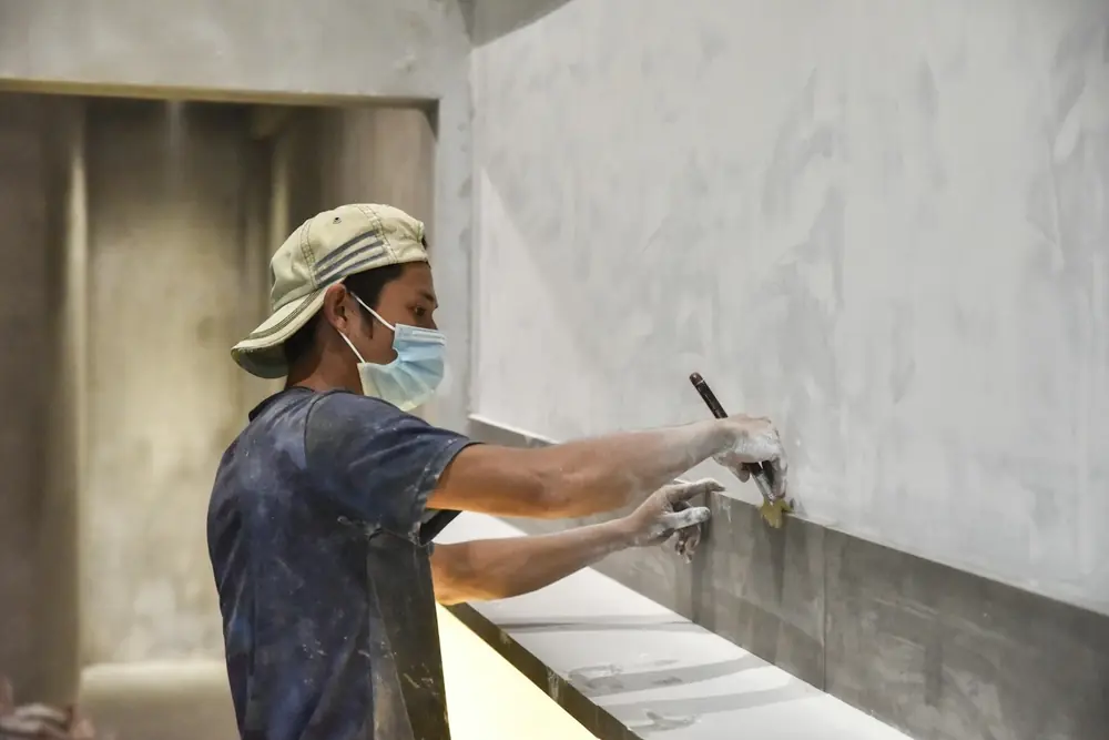 A worker in a dust mask patching a wall