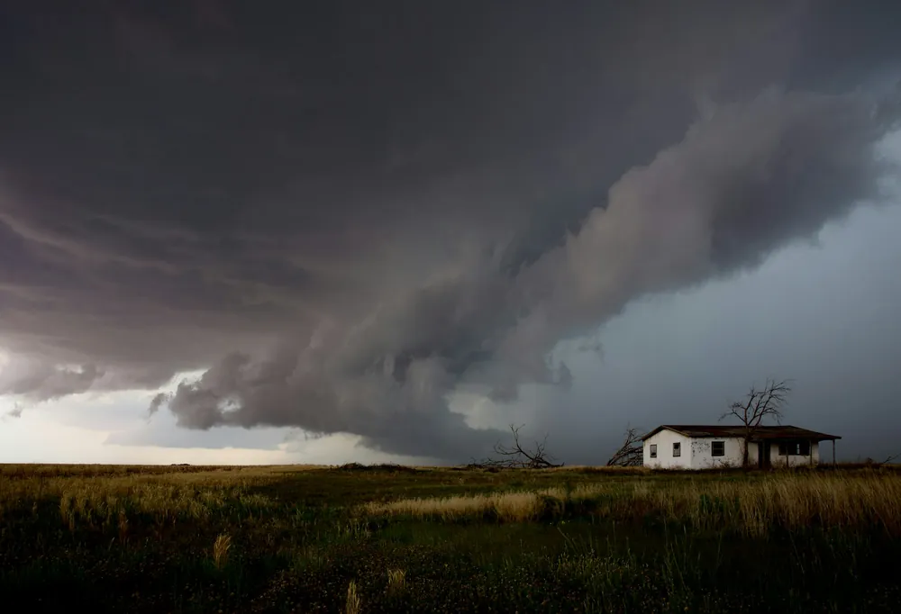 A storm cell building over a lone house on open ground