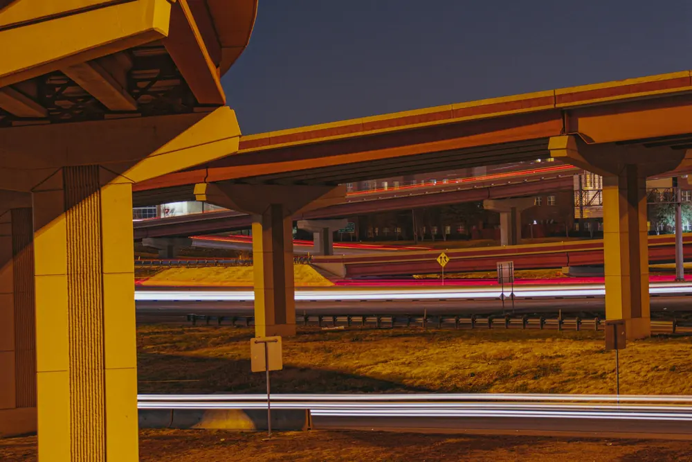 Freeway overpasses at dusk, with light trails from the traffic underneath