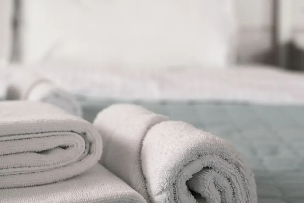 Rolled white towels on a freshly made bed