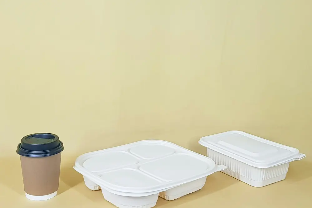 Empty takeaway containers and a coffee cup on a pale yellow table