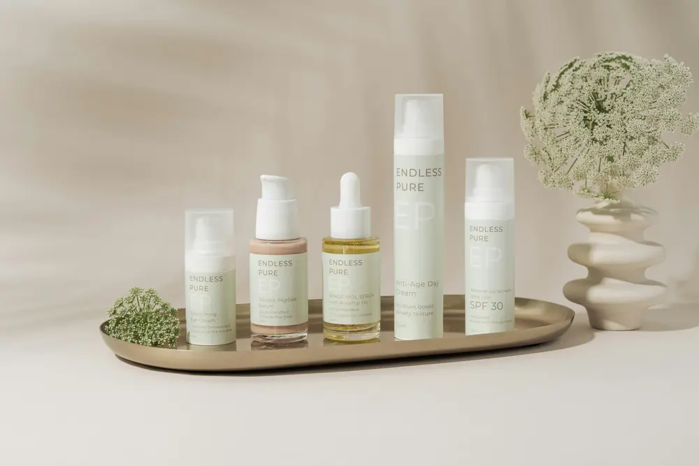 A tray of skincare bottles beside a small vase
