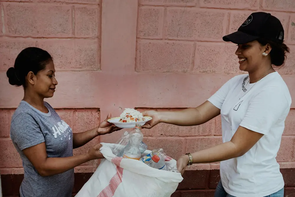 A volunteer handing a bag of food to a woman