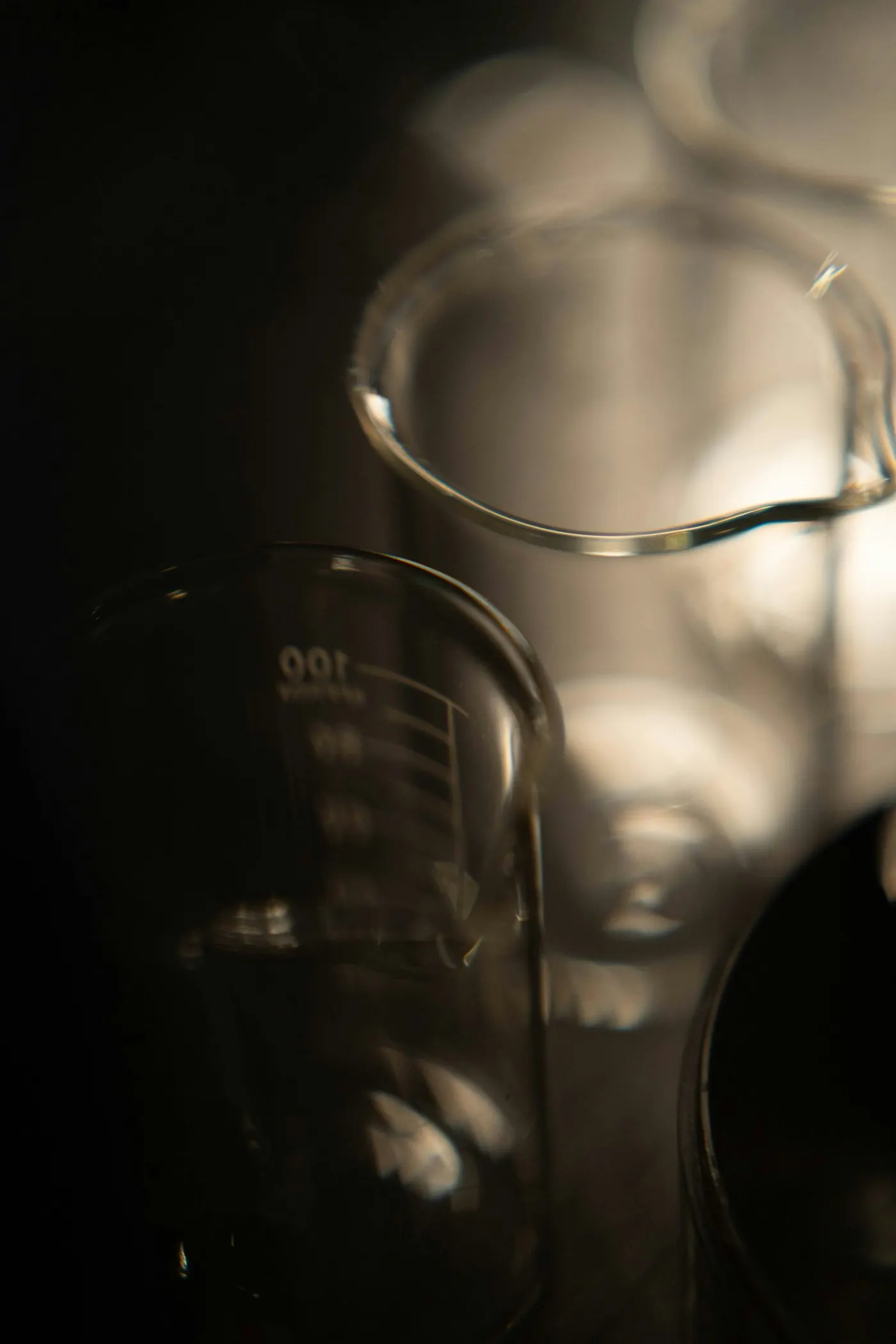 A glass laboratory beaker in low light