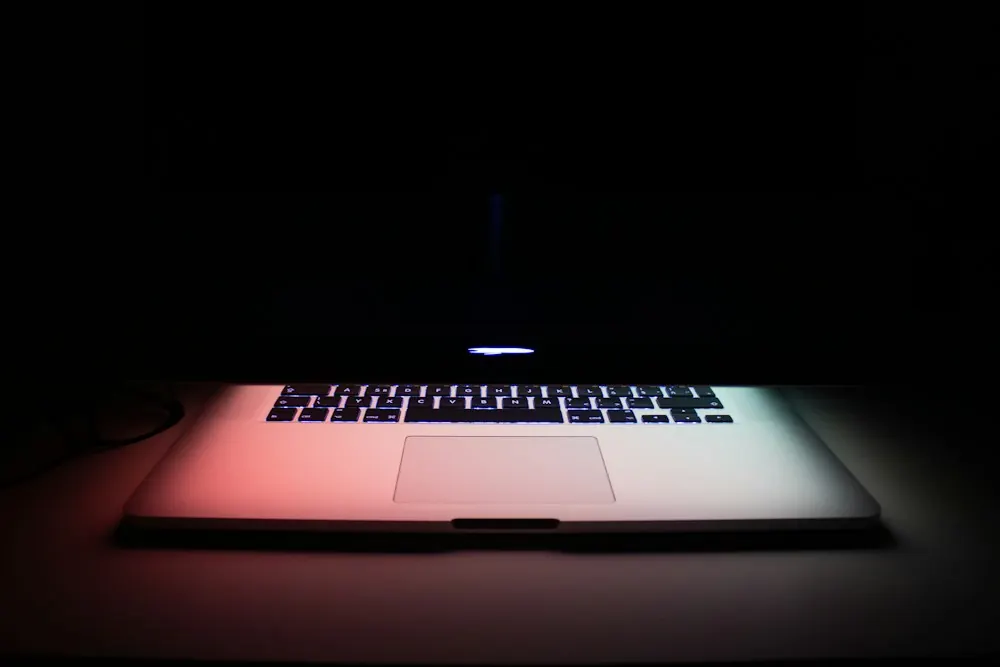 A laptop glowing on a dark desk