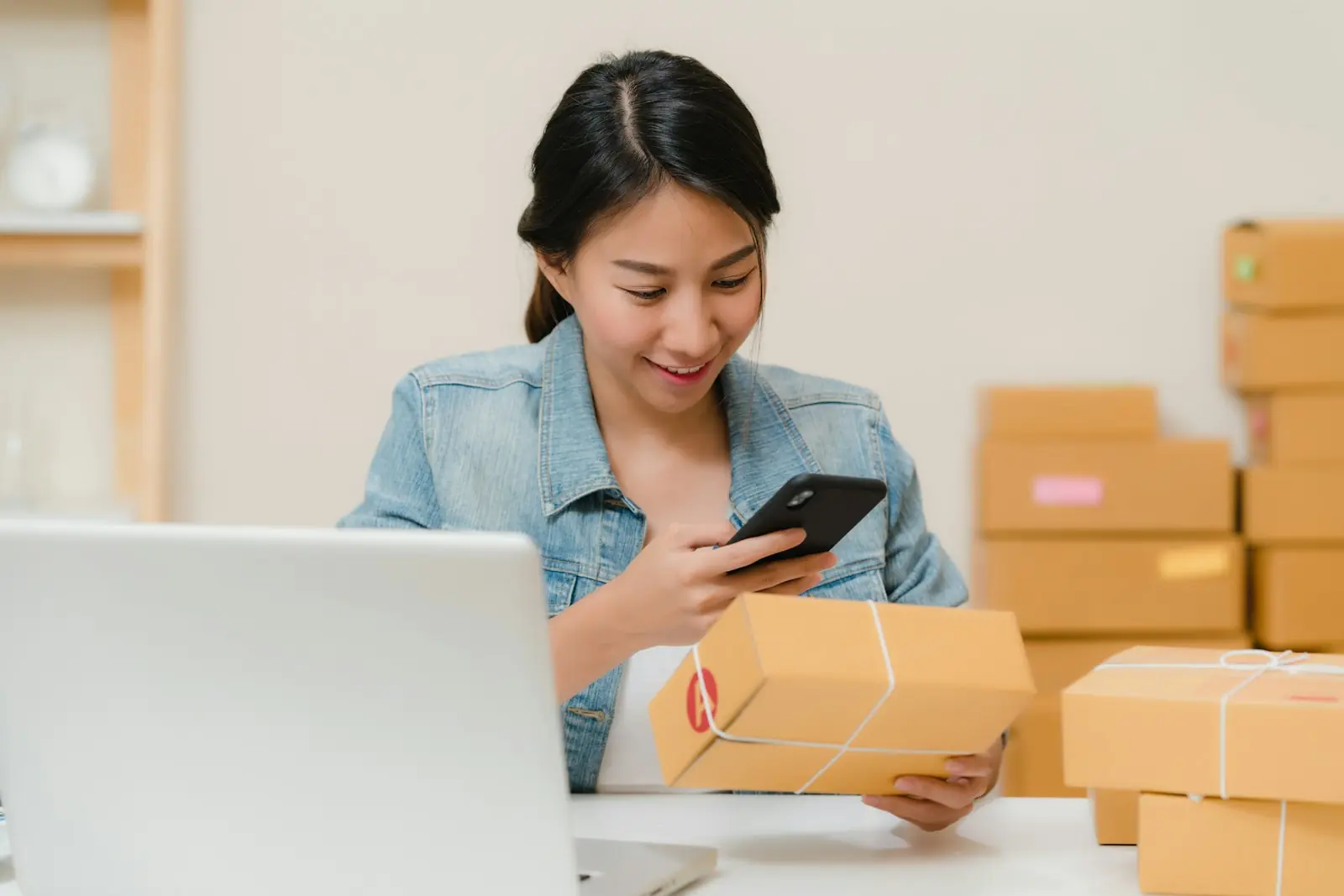 A founder checking an order on a phone beside packed boxes