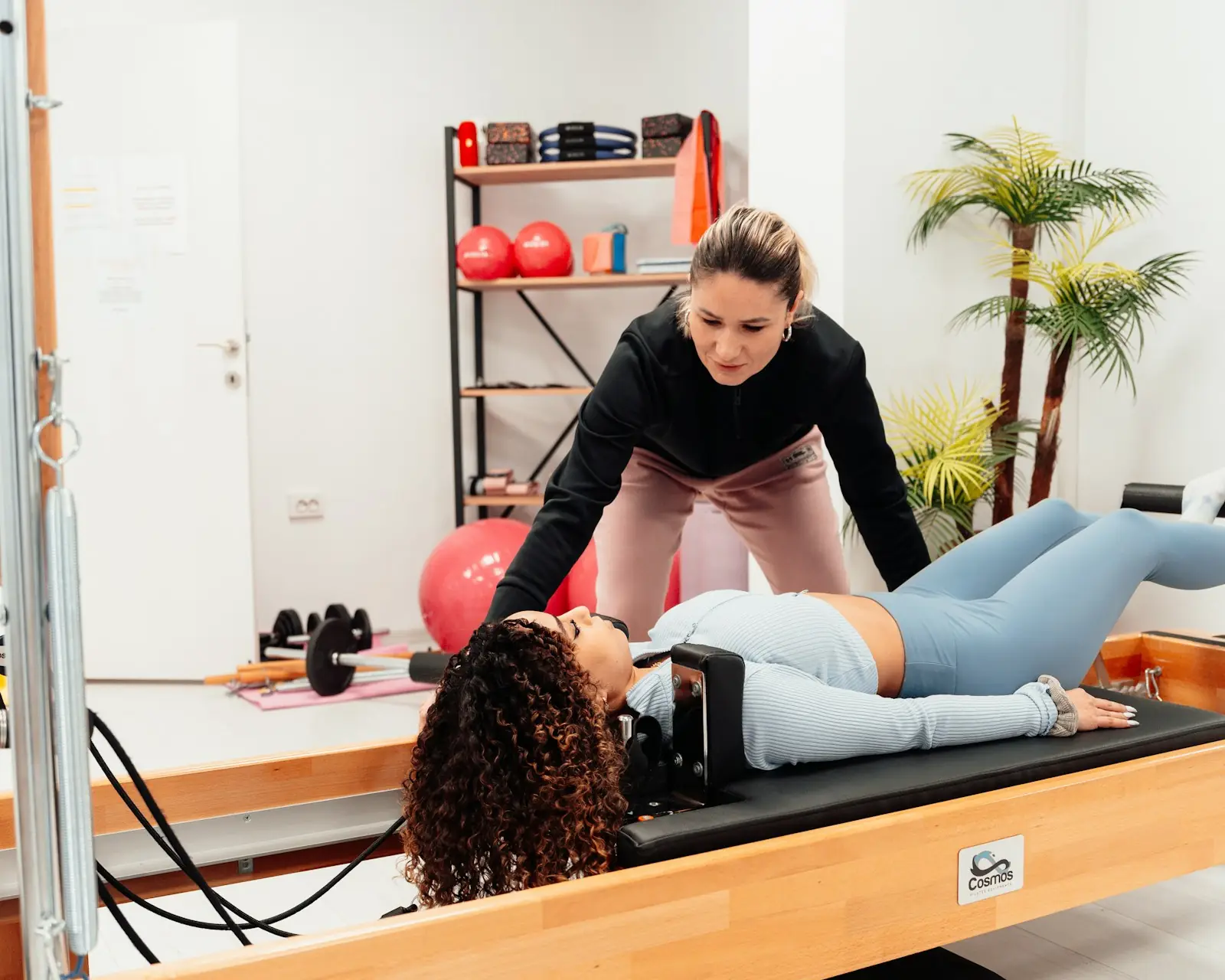 An instructor adjusting a client's position on a reformer