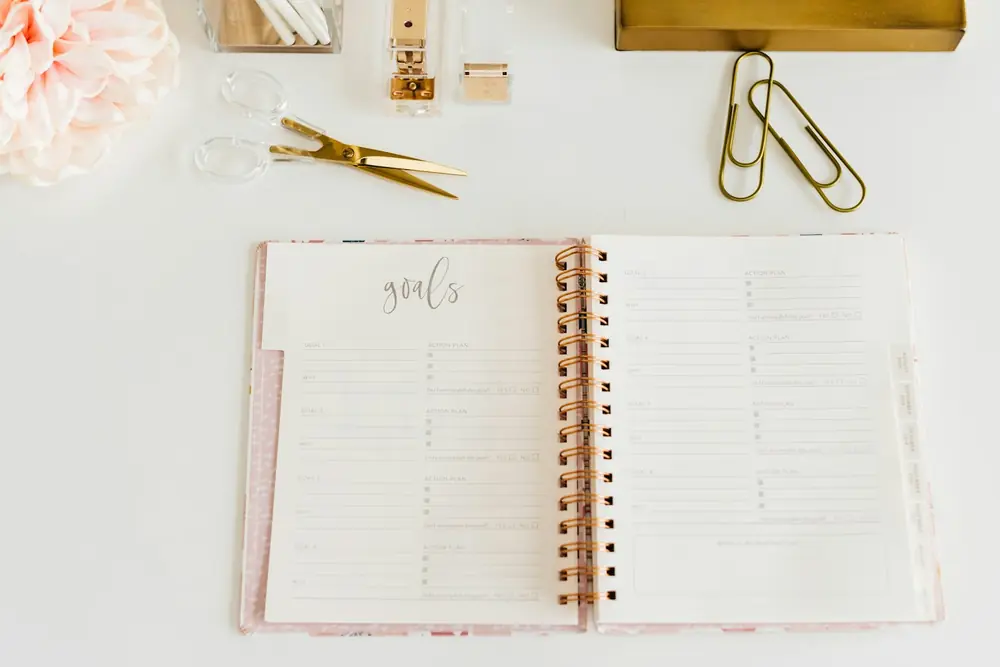 An open planner beside scissors and paper clips