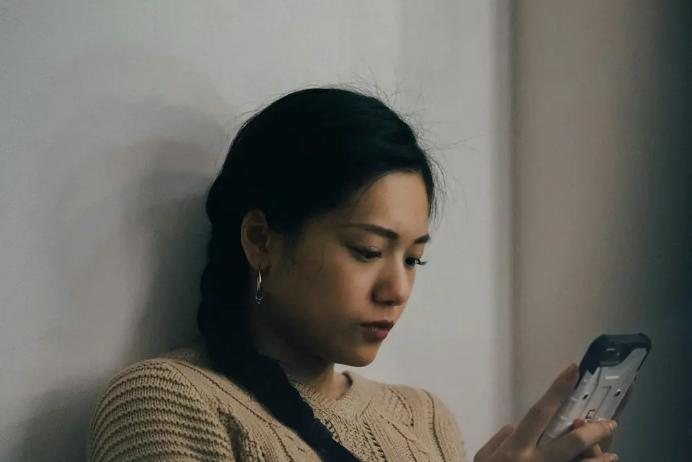 A woman reading her phone against a wall