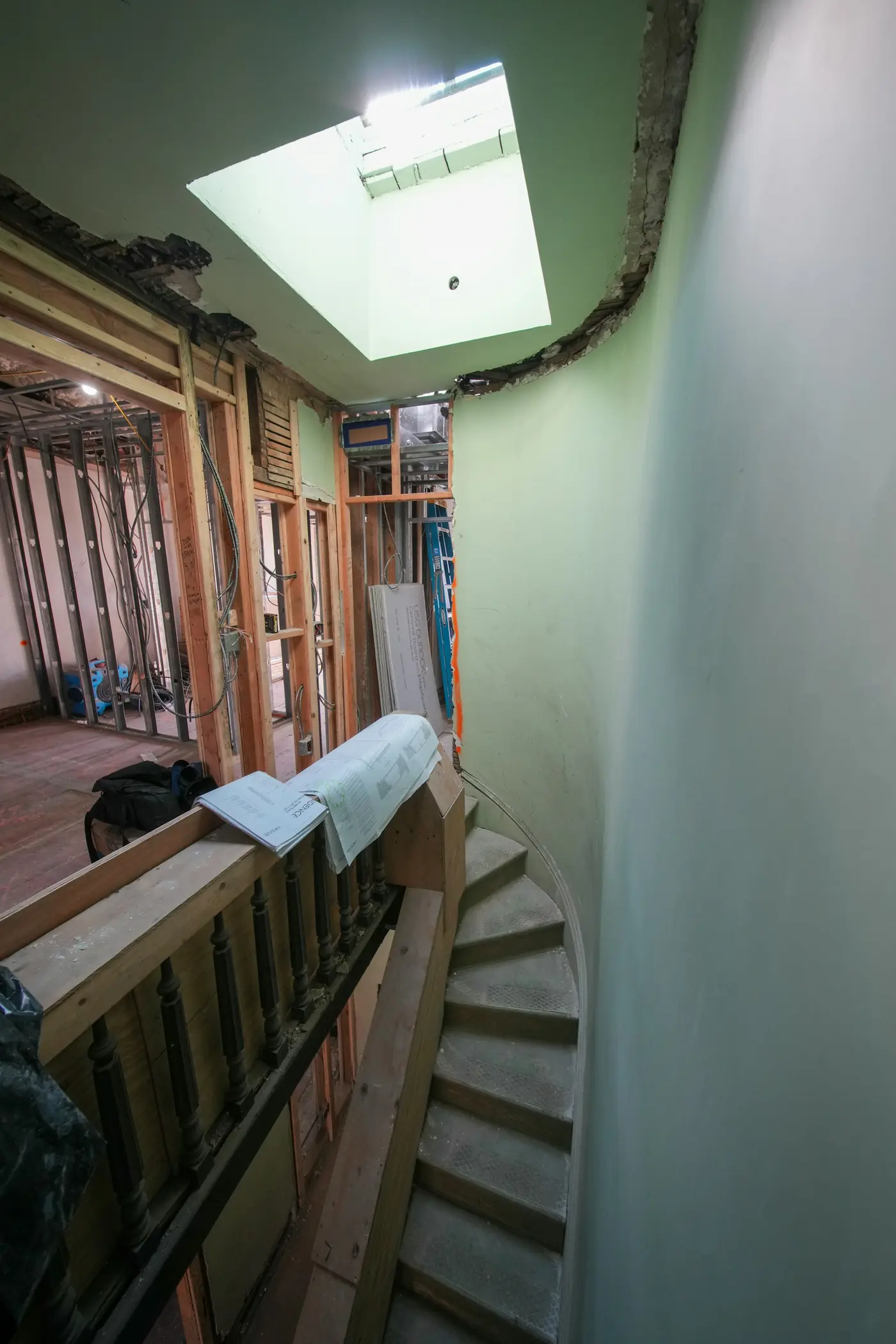 A stairwell stripped to the studs under a skylight