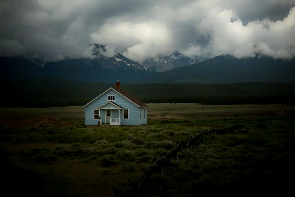 A lone house on open land under heavy clouds