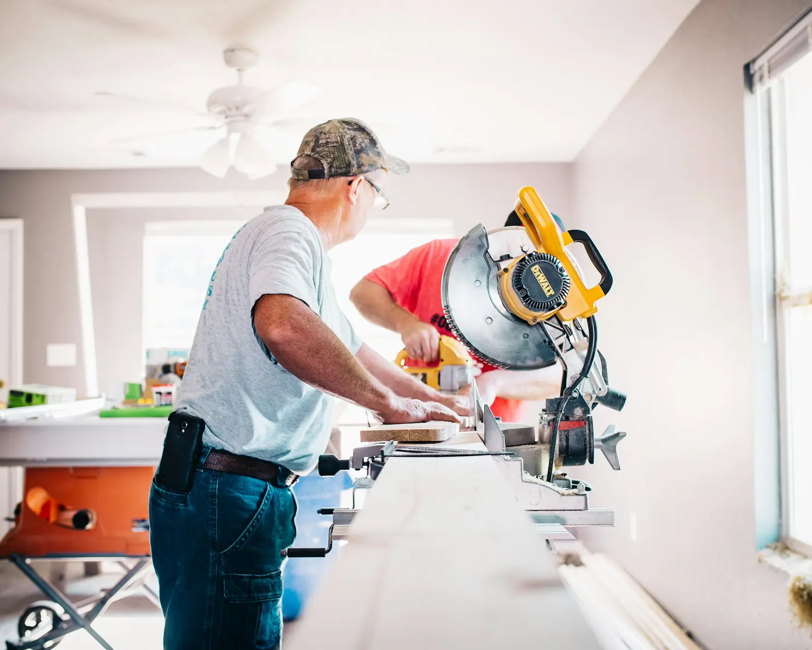 A contractor cutting trim with a miter saw in a renovated room