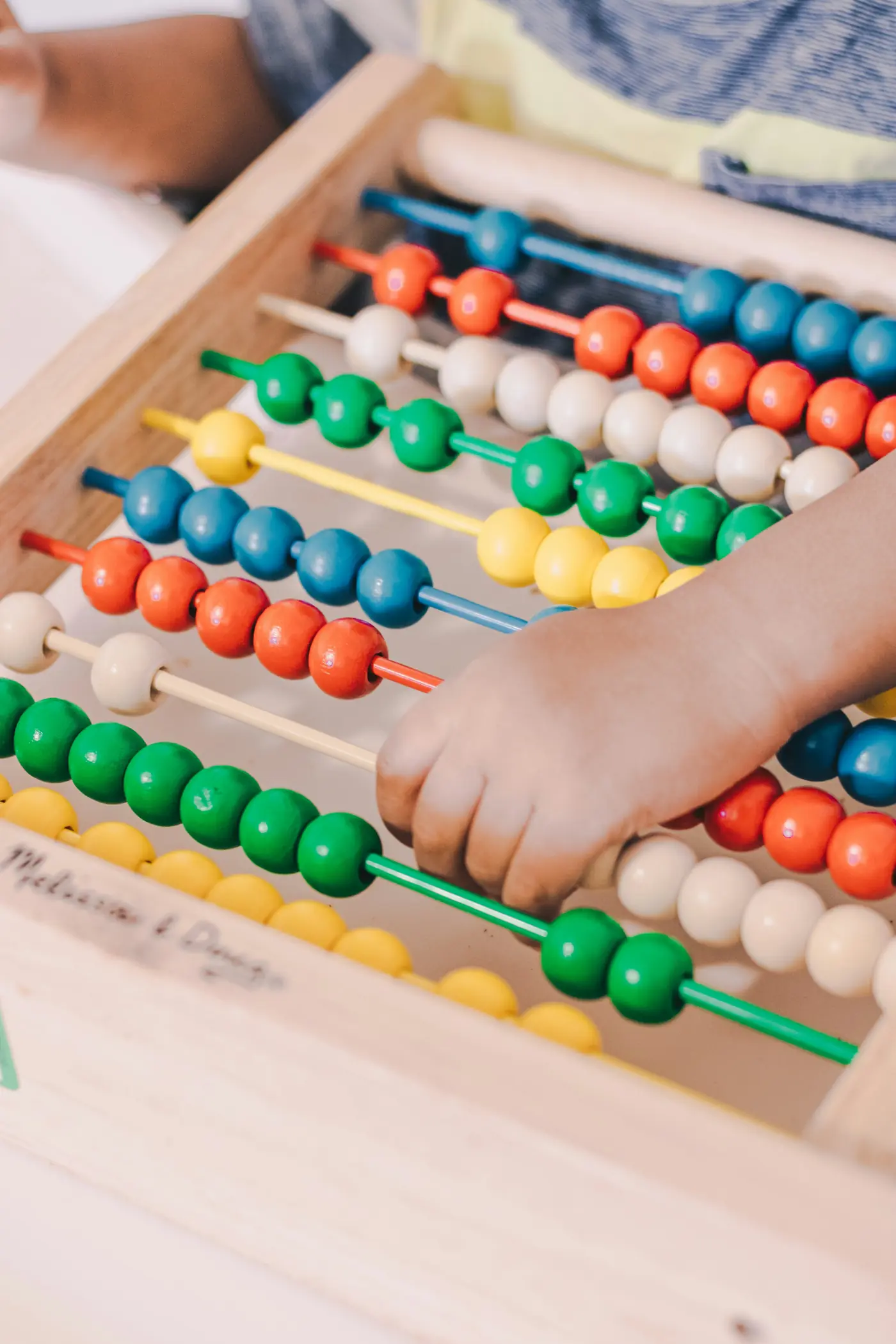 A child counting beads on a wooden abacus