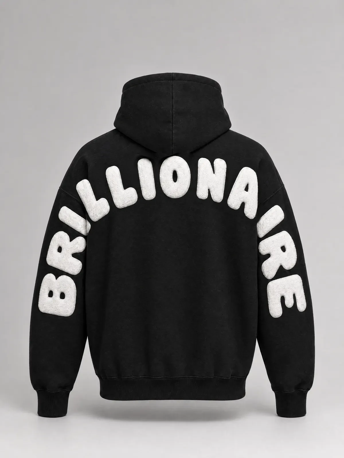 The back of a black hoodie, arms down: BRILLIONAIRE in raised white letters arches over the upper back and turns down both sleeves