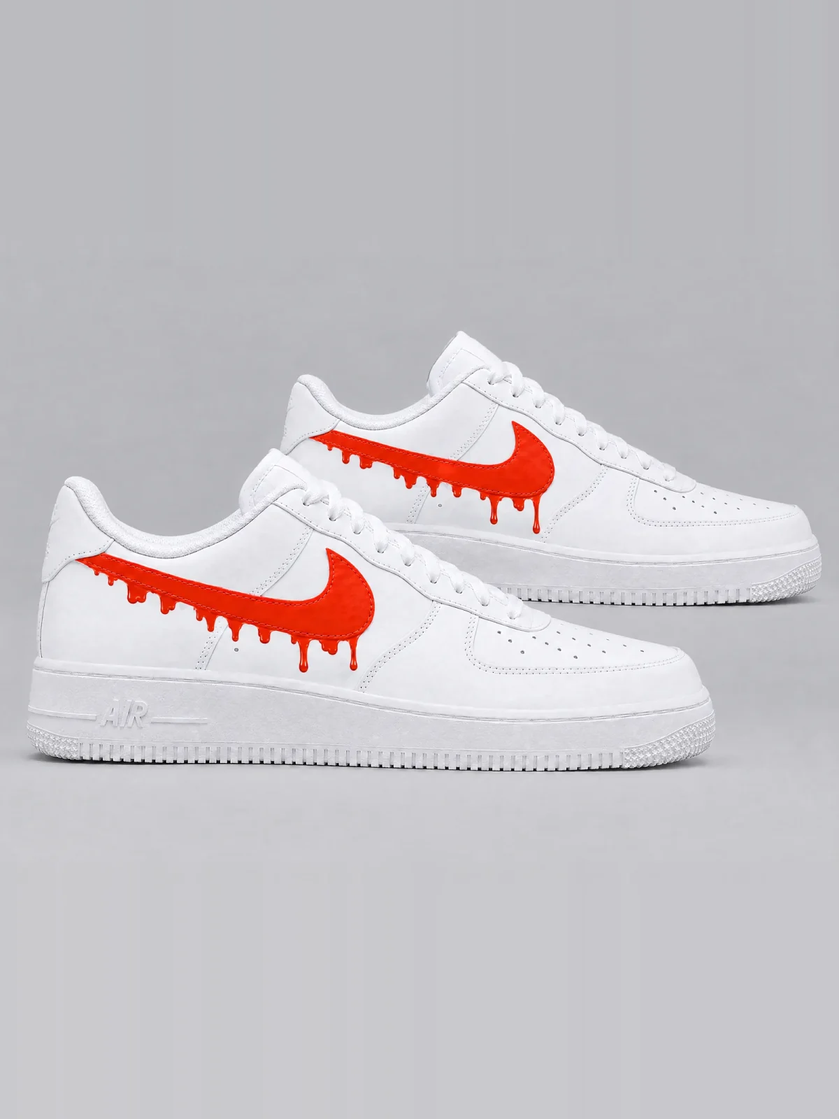 A pair of white leather low-top sneakers with white laces, the side logo sprayed in orange and dripping down in a soft, skyline-like row