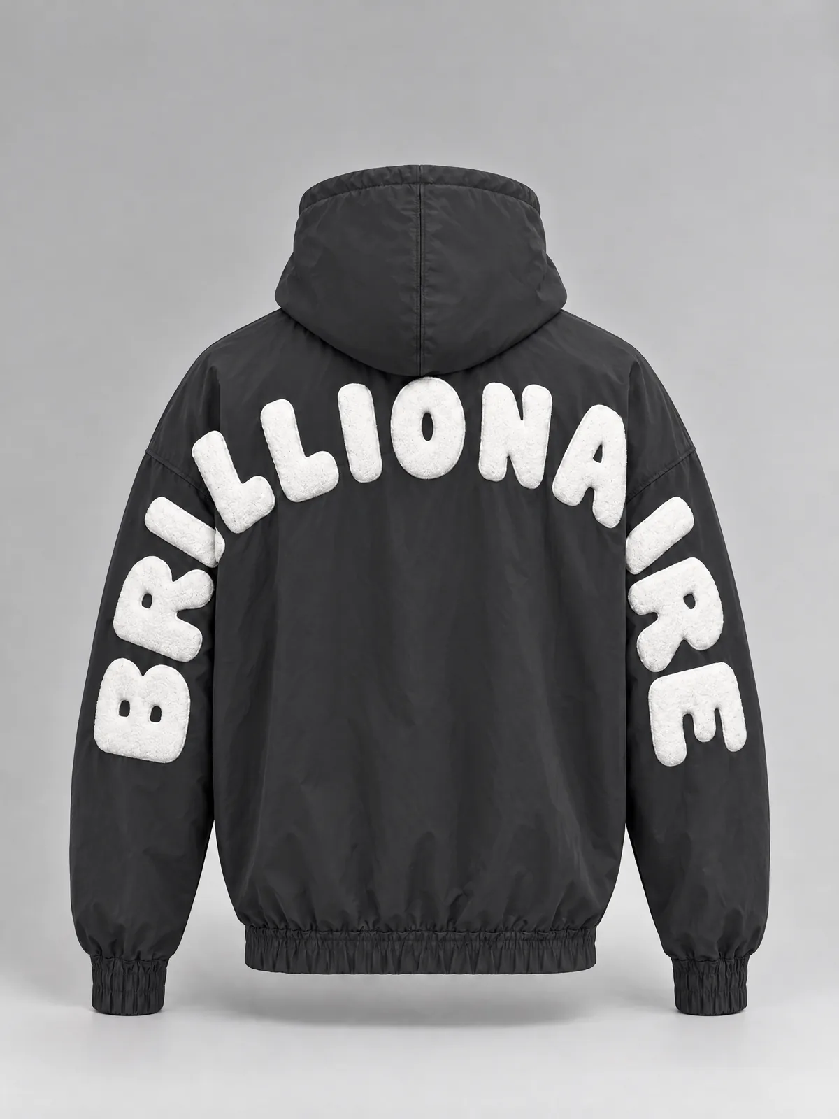 The back of a dark grey nylon zip-up hoodie: BRILLIONAIRE in raised white letters arches over the upper back and turns down both sleeves