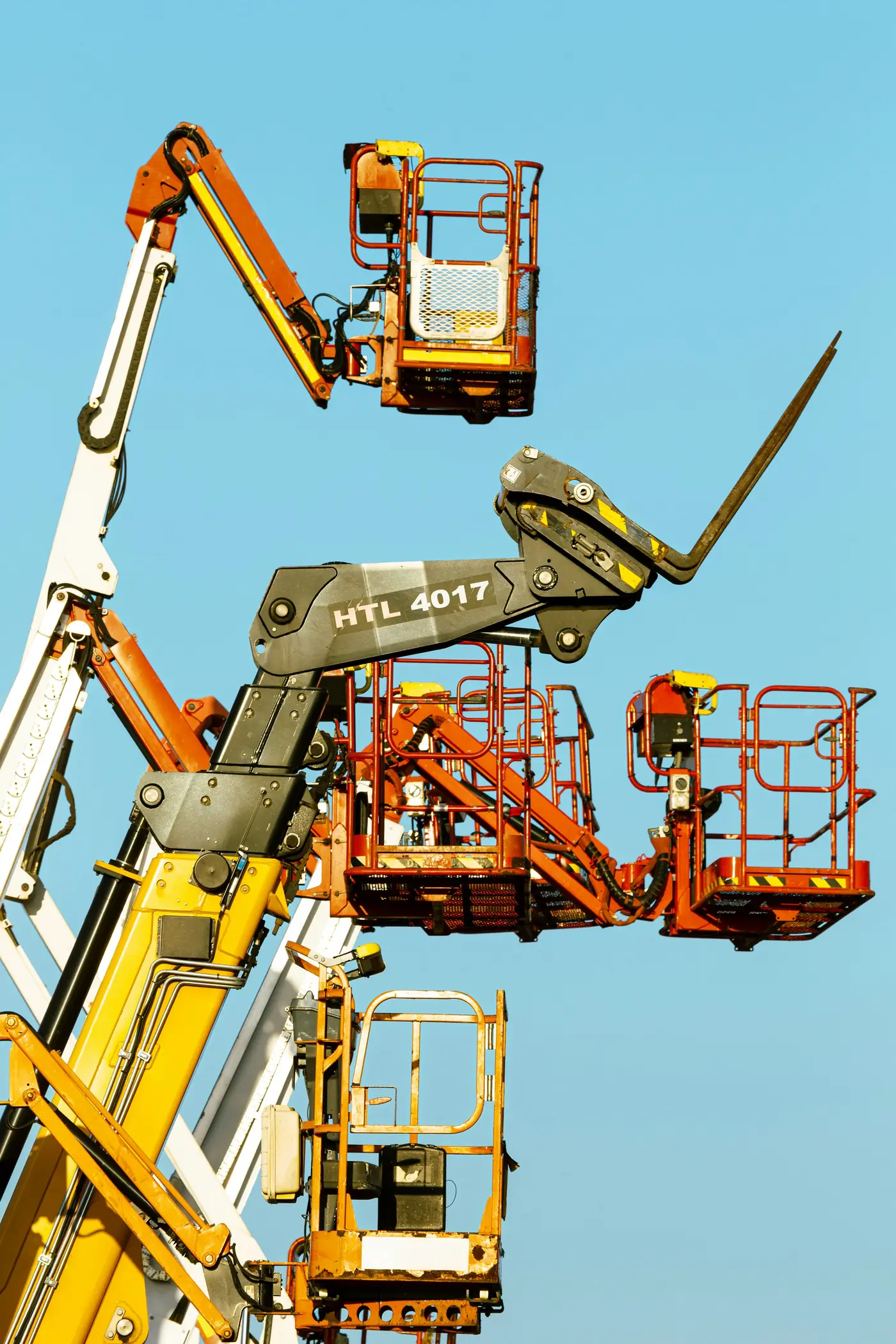 Boom lift baskets raised against a clear blue sky