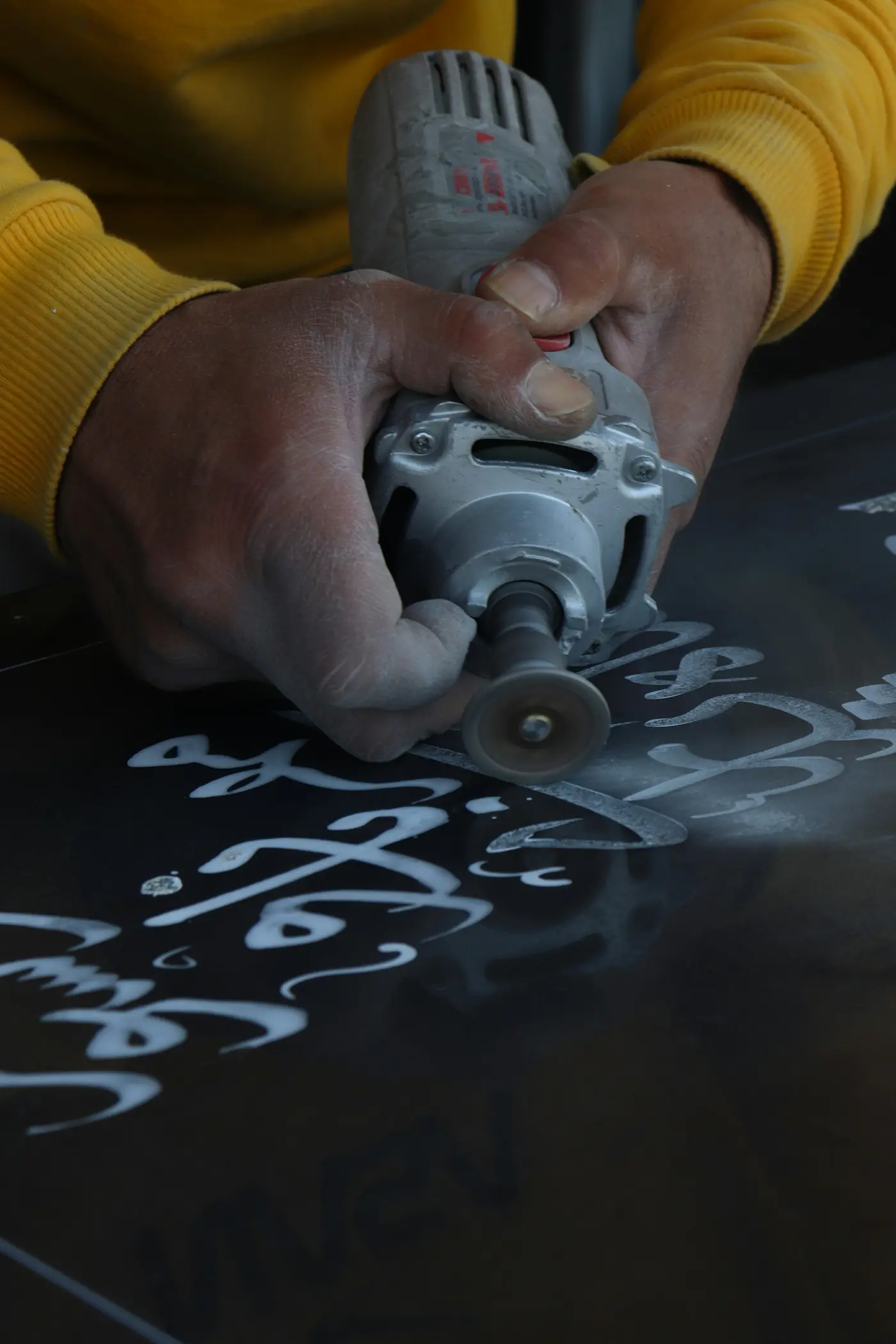 Hands guiding a rotary tool along cut lettering