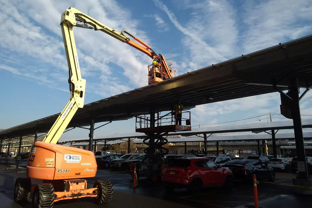 An articulating boom lift raised against a parking canopy