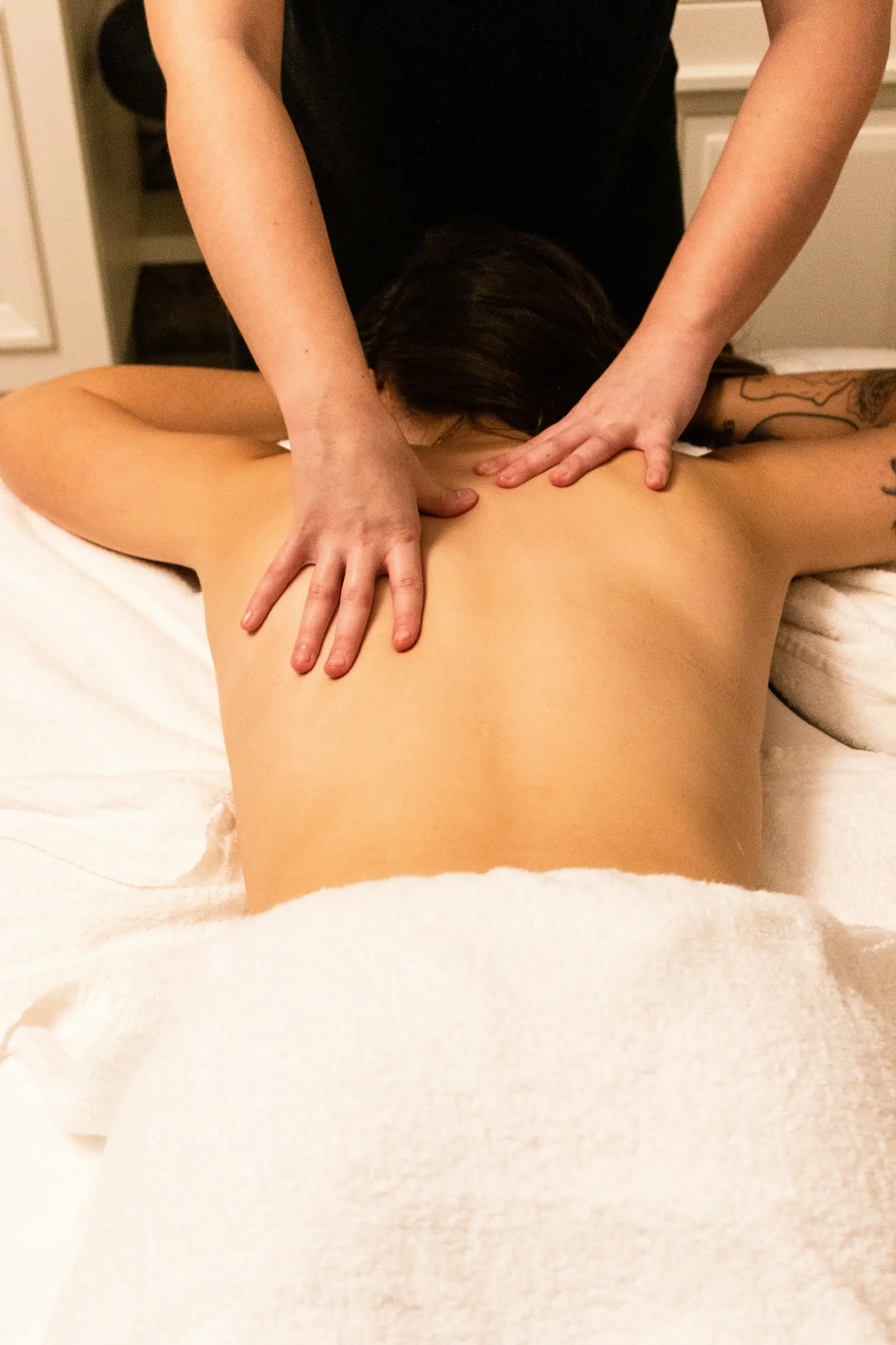 A therapist&rsquo;s hands working a client&rsquo;s shoulders