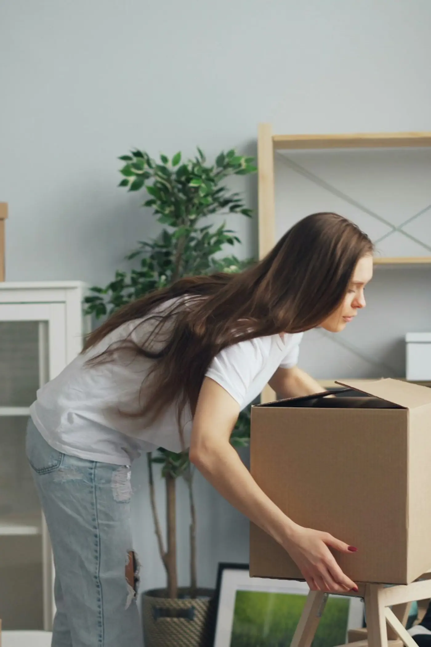 A woman lifting a packed box at home