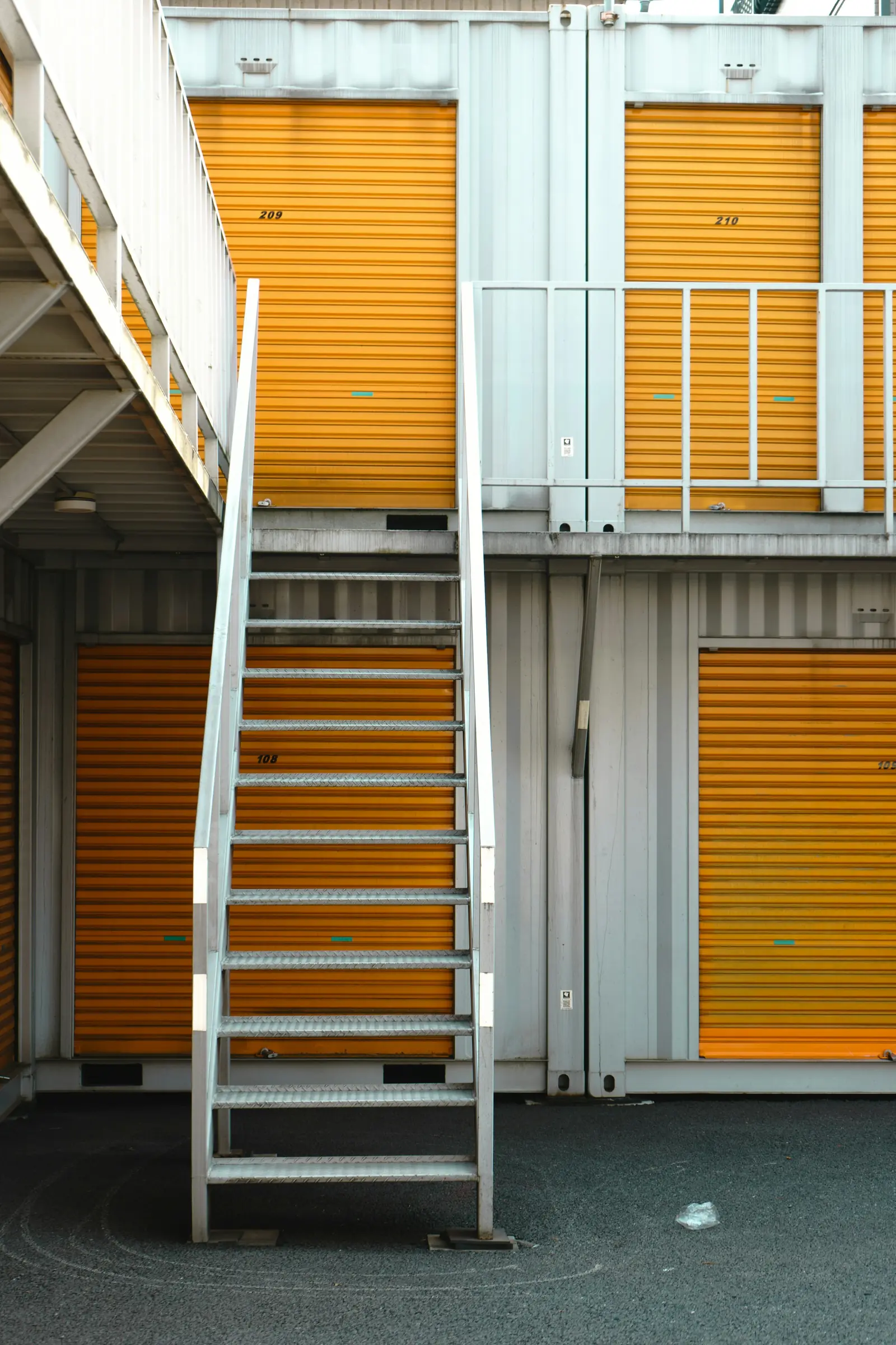 Metal stairs up to a second row of orange unit doors