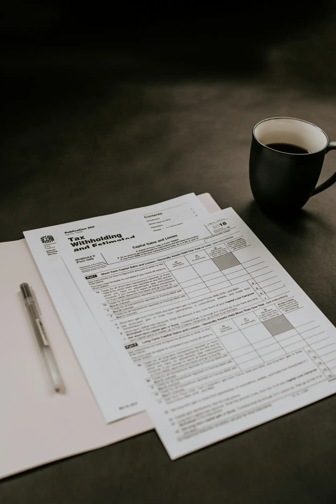 A coffee mug beside a stack of tax forms