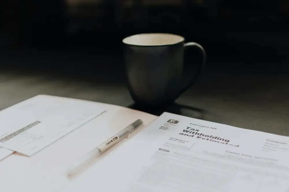 A coffee mug beside an open folder of tax forms
