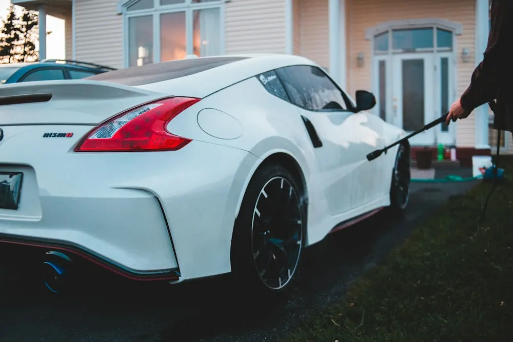 A white sports car being washed outside a house