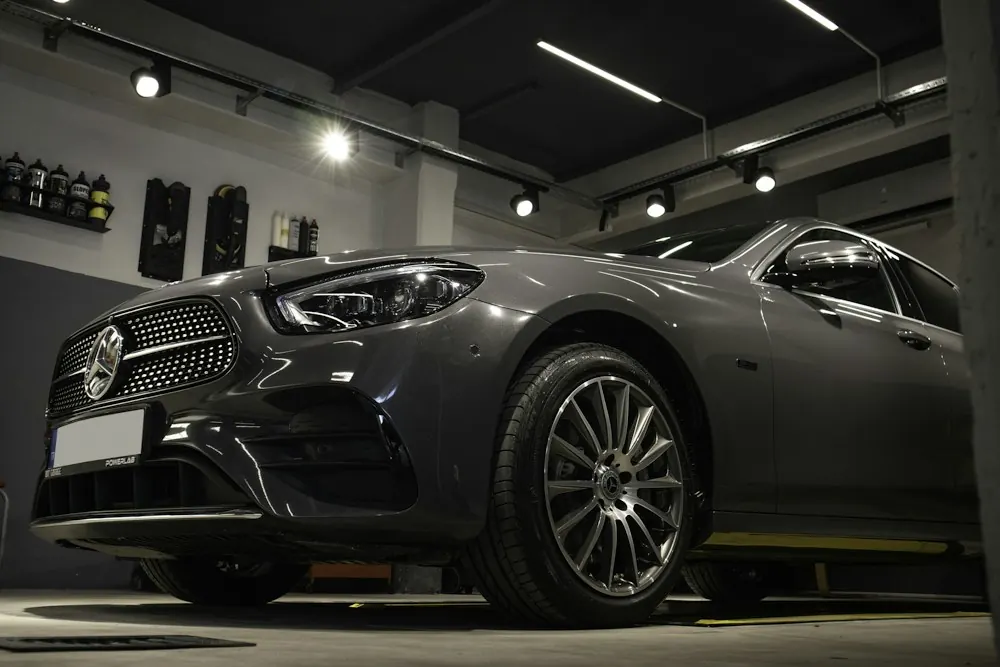 A single car under the lights of a quiet detail studio
